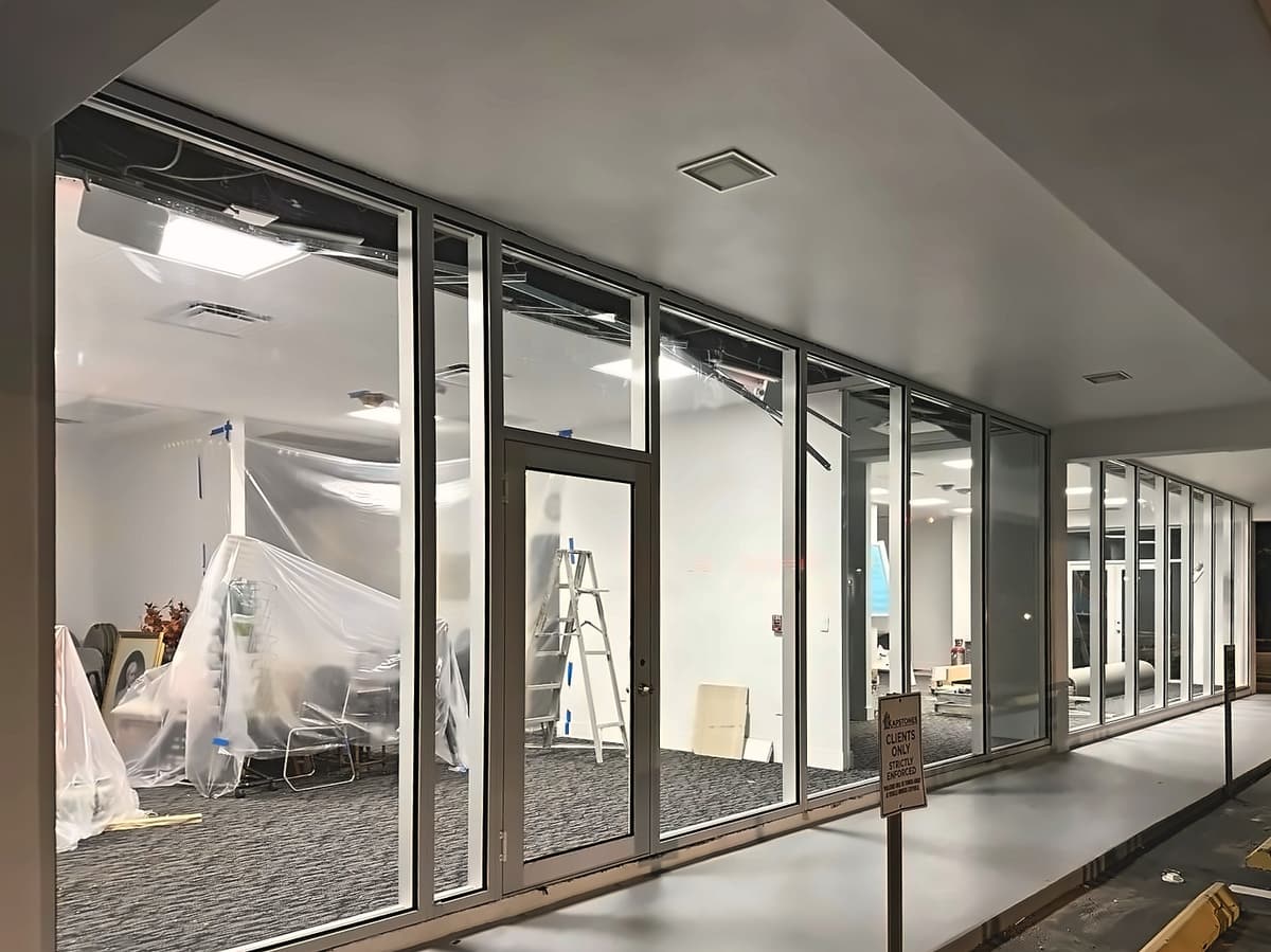 Commercial glass storefront wall with a glass door, seen at night