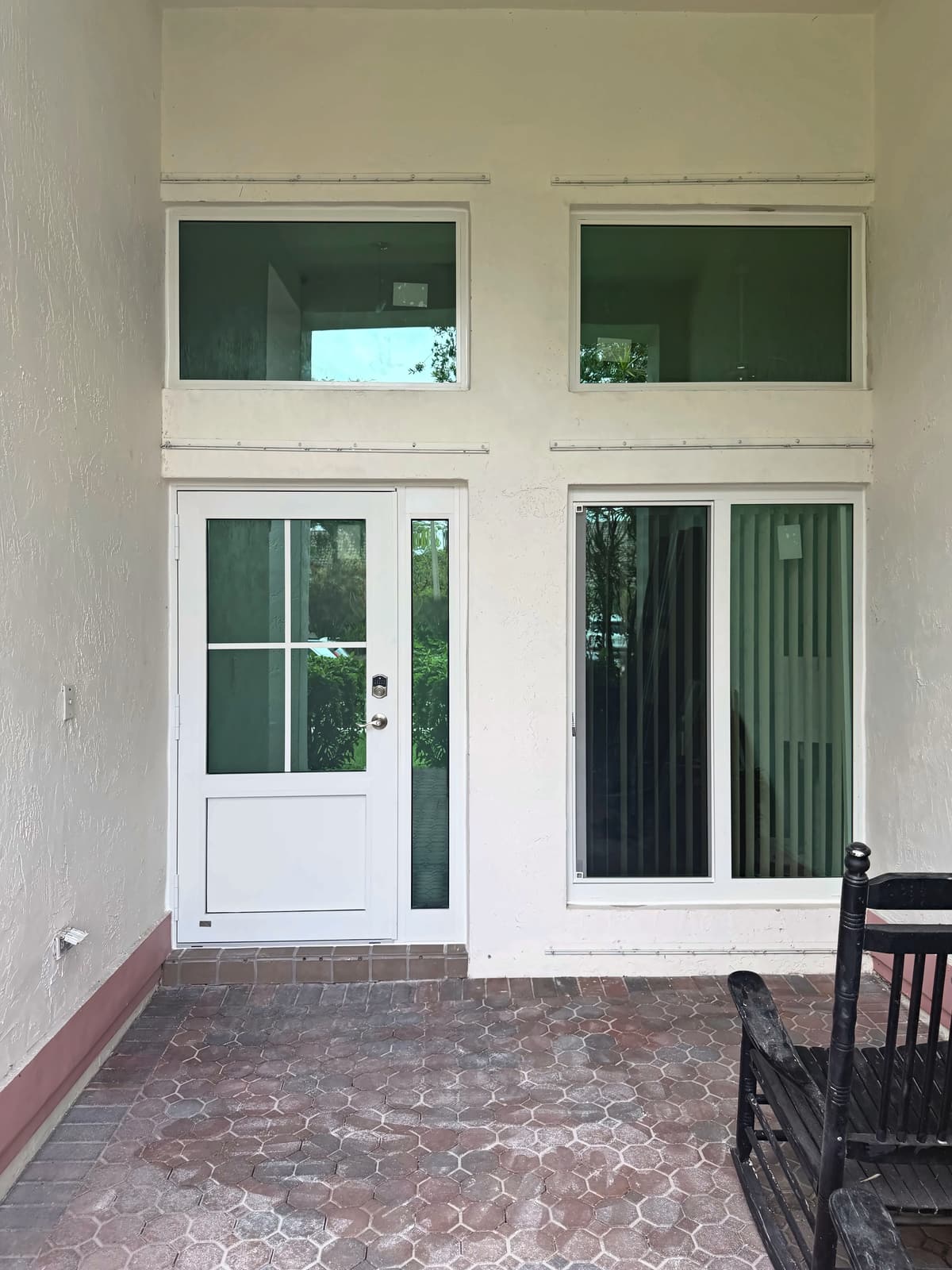 White entry door with a sidelite, a tall window and two transom windows above